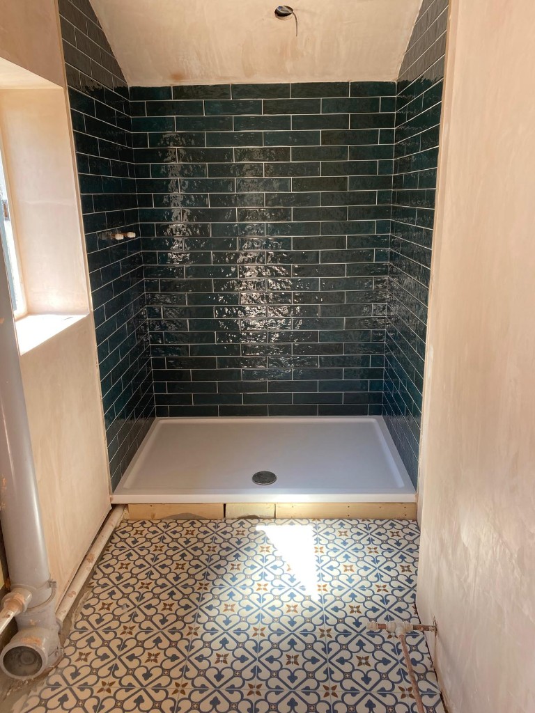 Walk-in shower area with green wall tiles during installation