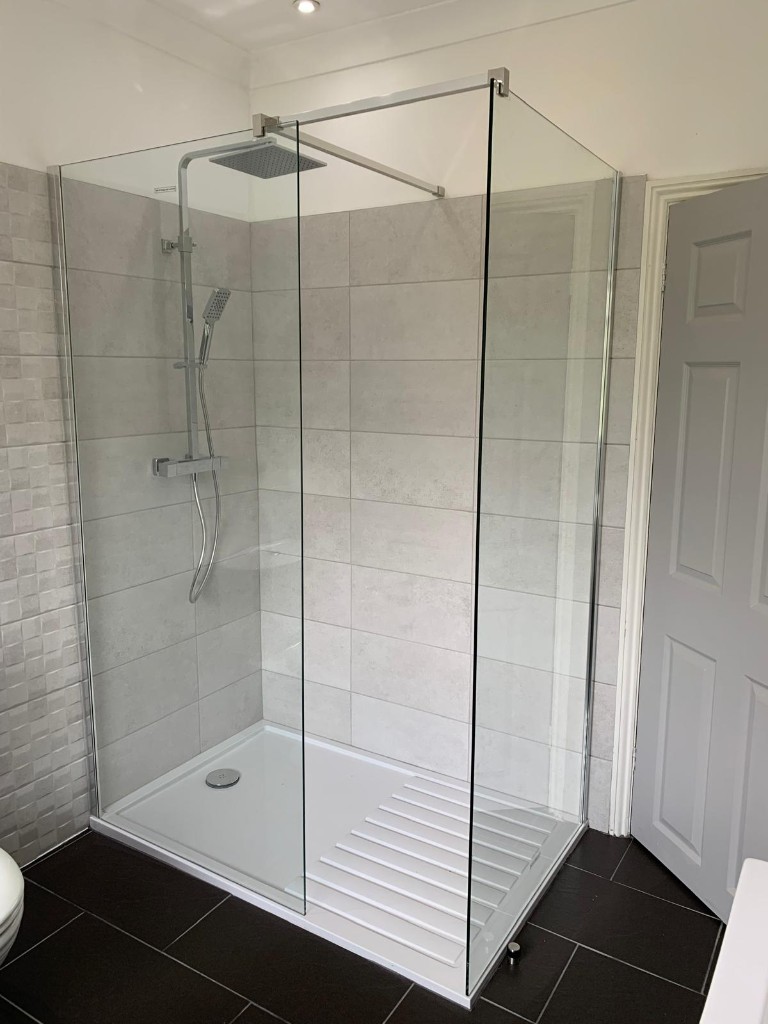Walk-in shower installation with grey wall tiles and chrome rainfall shower
